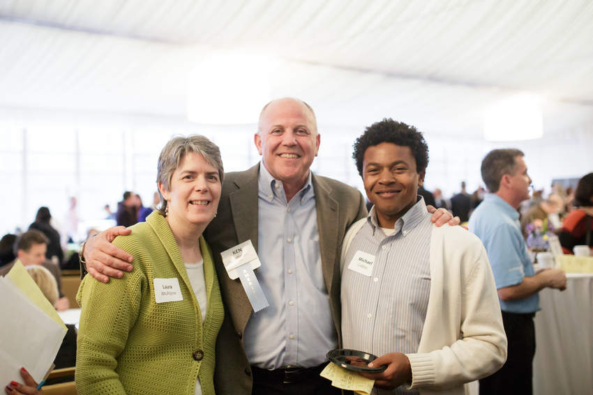 Laura McAlpine stands with two people at an event.